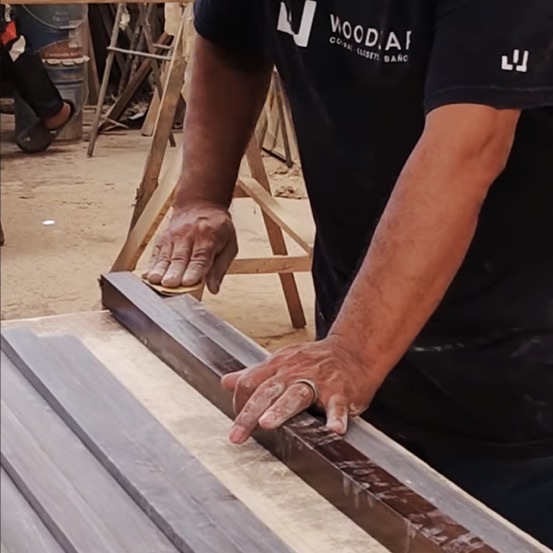 Manos de carpintero lijando una pieza de madera
